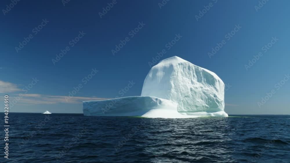 Immense ice berg floats off a coast in a cold sea Immense ice berg floats off a coast in a cold sea