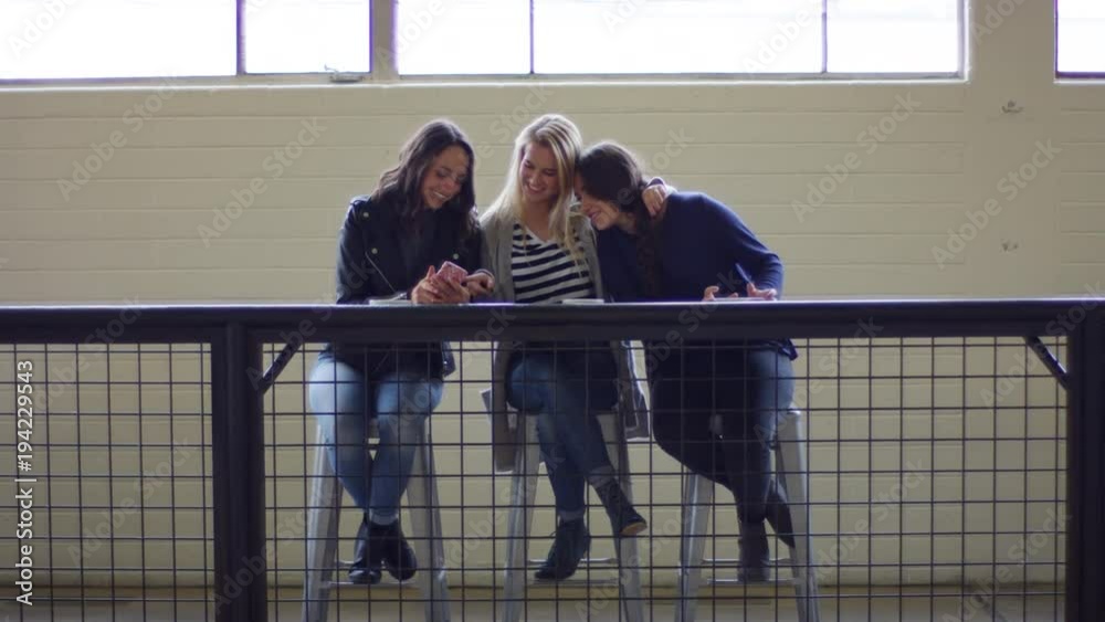 Group Of Friends Look At Photos On Smartphone And Crack Up Laughing ...