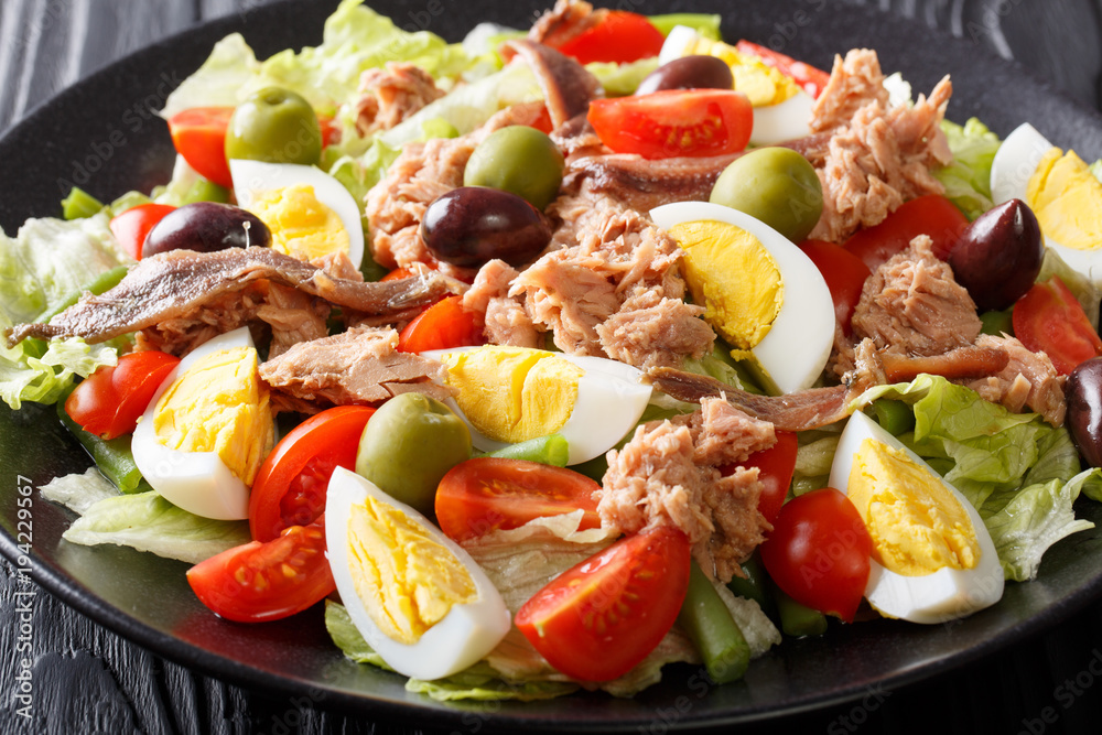 French nicoise salad with fresh vegetables, eggs, tuna and anchovies close up. horizontal French nicoise salad with fresh vegetables, eggs, tuna and anchovies close up. horizontal
