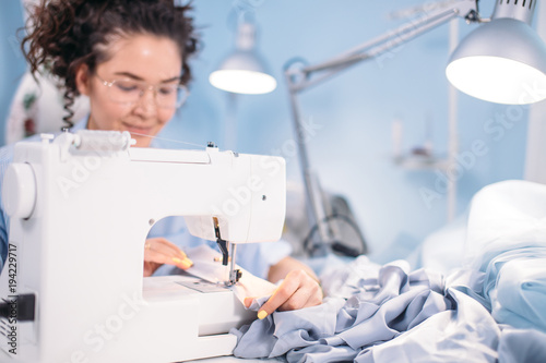 side view photo of sewing machine and dressmaker in working process. sewing business. needlework photo