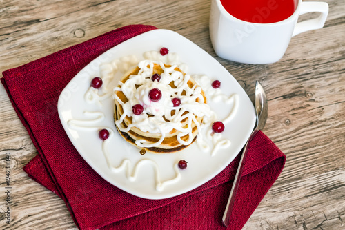 Fresh baked muffins for Breakfast in white plate, decorated with sour cream and lingon berries, with a berry juice in the Cup, top view 