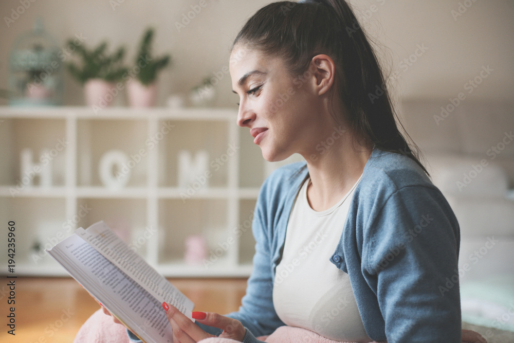 Obraz premium Young woman sitting on floor and reading book.