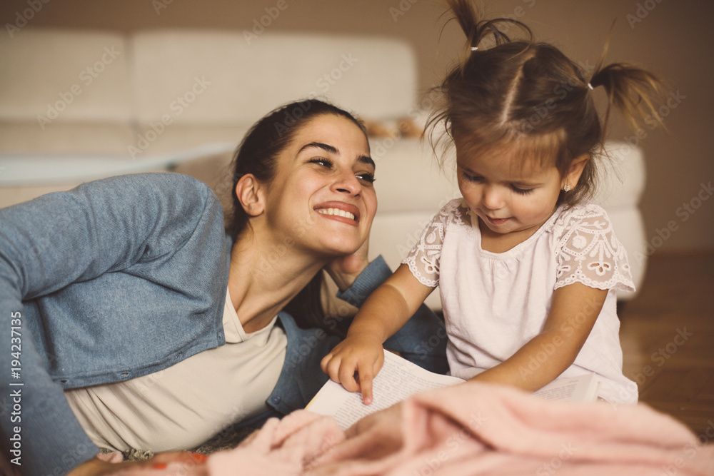 Mother and daughter playing together at home. Mother teaching her daughter to reading. Mother and daughter playing together at home. Mother teaching her daughter to reading.