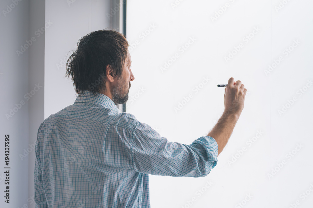 Businessman in office writing on whiteboard Businessman in office writing on whiteboard