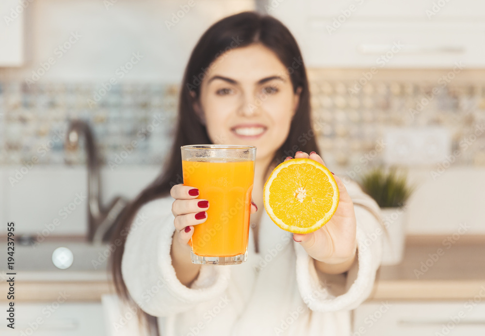 Beautiful girl wears white bathrobe with glass of orange juice and cuted fruit, kitchen morning sunset view Beautiful girl wears white bathrobe with glass of orange juice and cuted fruit, kitchen morning sunset view