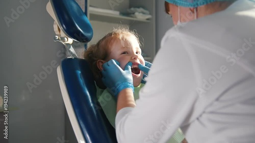Girl on reception at the dentist, the stomatologist cleaning and watering the child's teeth, girl smiling and talking photo