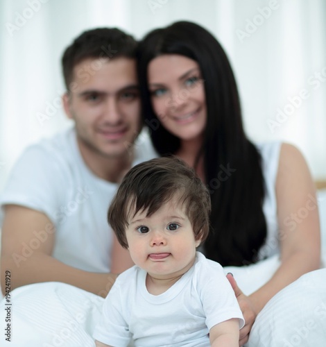 Happy couple and son sitting in bed