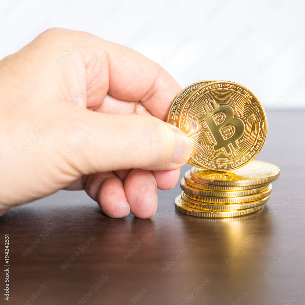 One Bitcoin holding in hand and others beside One Bitcoin holding in hand and others beside