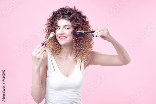 Closeup woman with makeup brushes near face.
