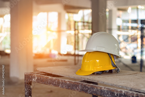 Yellow and white helmets are placed on the wooden table inside the construction area.