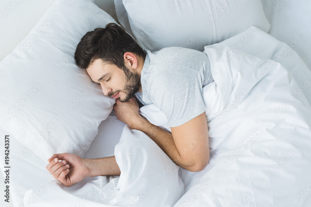 top view of bearded man sleeping on bed in bedroom - obrazy, fototapety, plakaty 