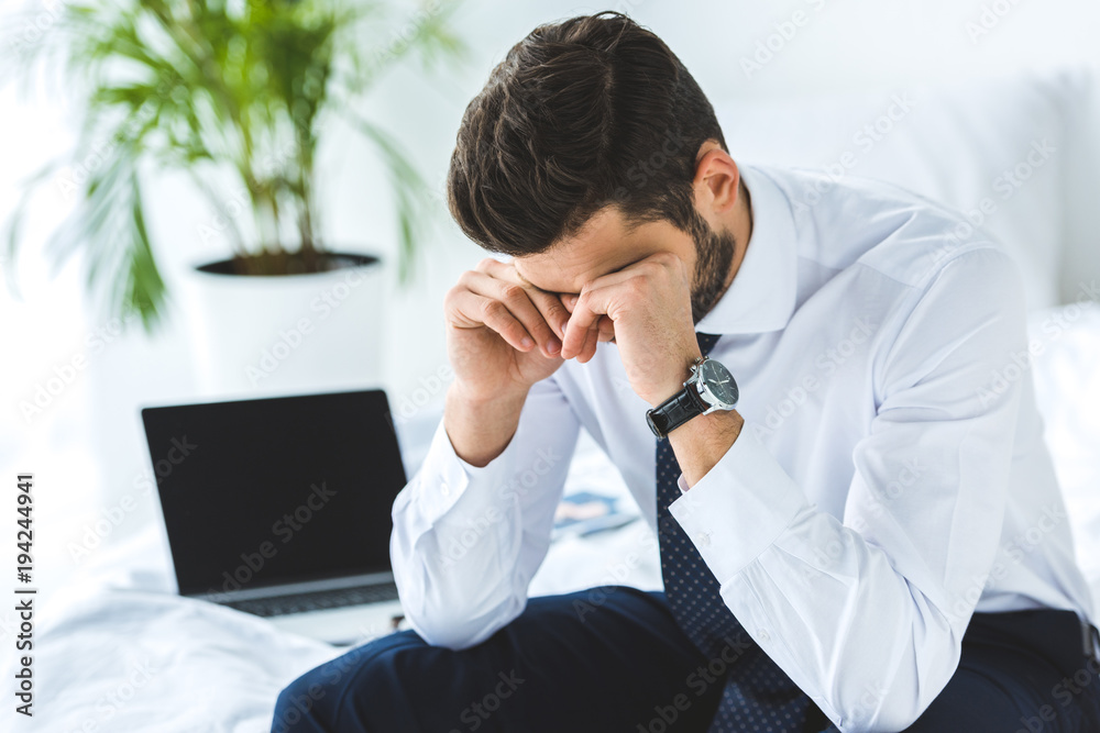 tired businessman sitting on bed with laptop tired businessman sitting on bed with laptop