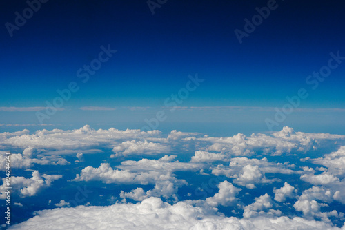 Blue sky and clouds below from airplane window