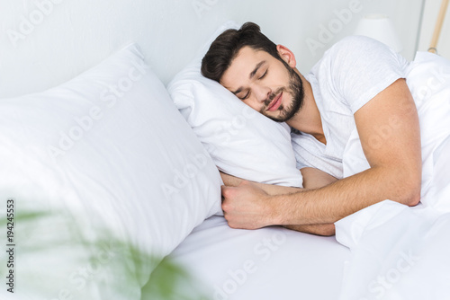 bearded man sleeping on bed in bedroom