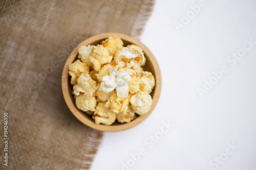 Salted popcorn in round wooden bowl with space on white background, movie night snack
