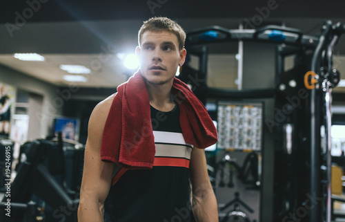 Horizontal shot of handsome sportsman resting after training at the gym with red towel on the shoulders with copy space for your text or advertising. Sport  healthy  lifestyle and people concept.