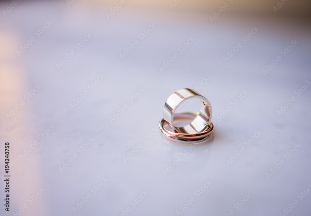 Golden wedding rings stand on each other on white marble table Golden wedding rings stand on each other on white marble table