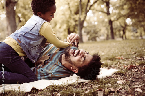 African American daughter and father in meadow.