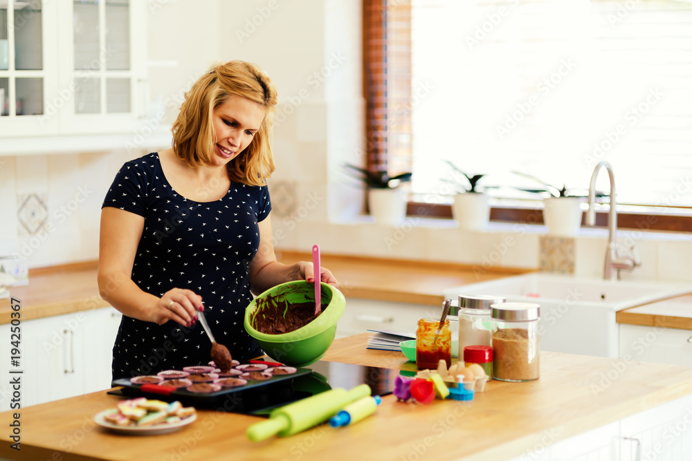 Beautiful pregnant woman baking muffins Beautiful pregnant woman baking muffins