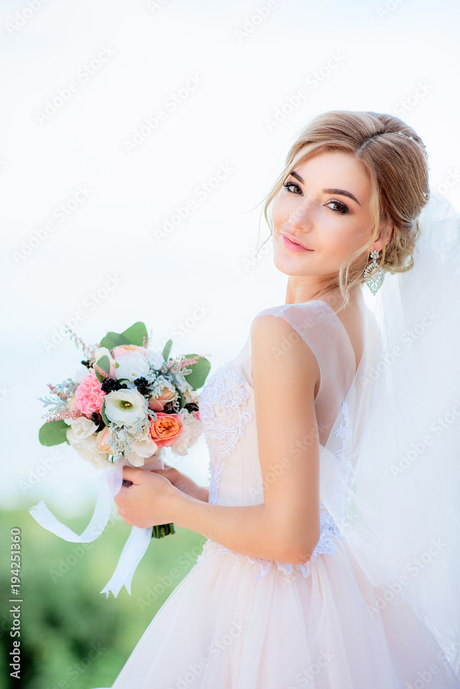 Portrait of a stunning bride with blonde hair holding peach wedding bouquet in her arms Portrait of a stunning bride with blonde hair holding peach wedding bouquet in her arms