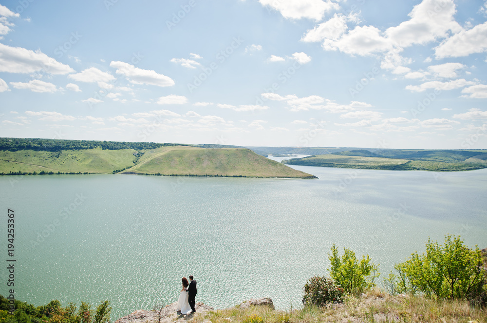 Wedding couple at breathtaking landscape with rock and lake. Wedding couple at breathtaking landscape with rock and lake.