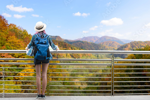 Westerner traveller woman with map in hand admiring view of atumn landscape in japan
