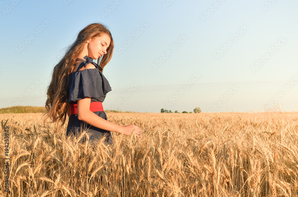 Young girl standing in the field and admiring the wheat flakes Young girl standing in the field and admiring the wheat flakes
