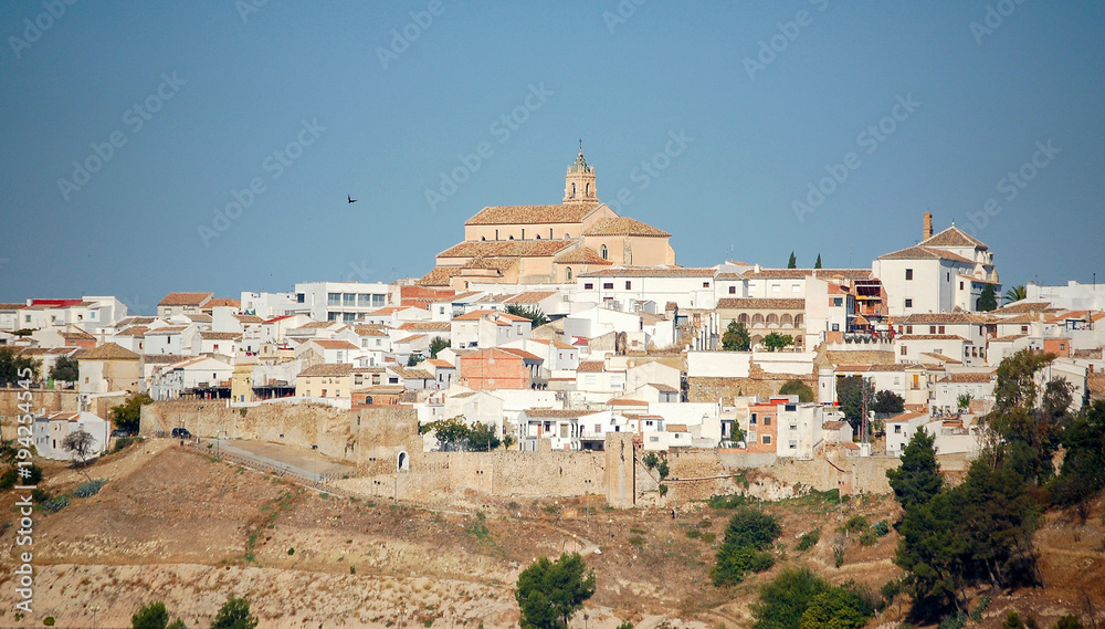 The Church of Santa Maria la Mayor between whitewashed houses and the blue sky - Baena, Andalusia, Spain