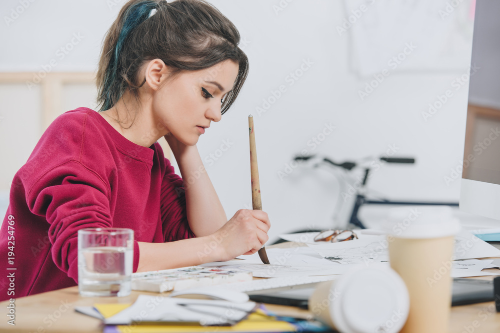 Attractive young girl drawing sketches by working table Attractive young girl drawing sketches by working table