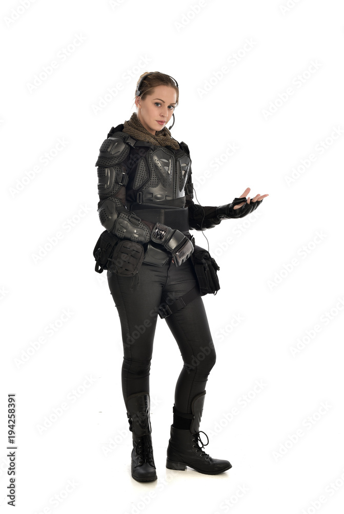 full length portrait of female  soldier wearing black  tactical armour with arms raised, isolated on white studio background.