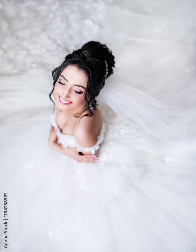 Look from above at brunette bride sitting on the floor in her rich wedding dress Look from above at brunette bride sitting on the floor in her rich wedding dress