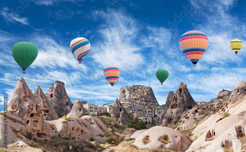 Uchhisar fortress and colorful hot air balloons flying over valley in Cappadocia, Anatolia, Turkey
