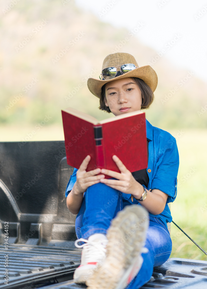 Woman wear hat and reading the book on pickup truck