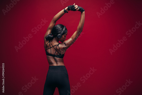 Female athlete with headphones stretching her arms
