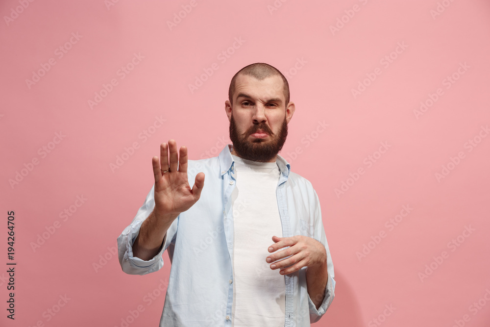 Young man with disgusted expression repulsing something, isolated on the pink