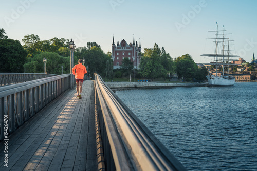 Young man runs on the bridge to the Skeppsholmen island in Stockholm at sunrise. photo