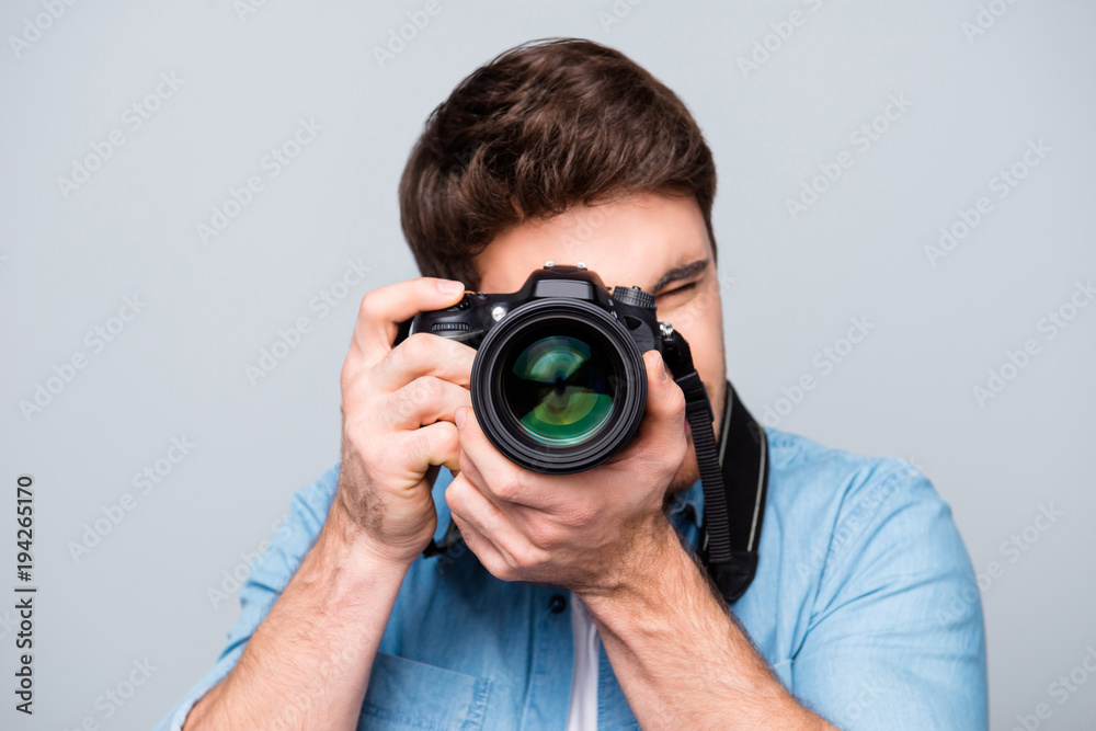 Portrait of guy in jeans shirt looking at photo camera, shooting photographs during excursion, making photosession over gray background - obrazy, fototapety, plakaty 