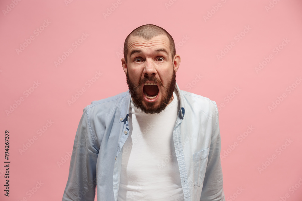 The young emotional angry man screaming on pink studio background The young emotional angry man screaming on pink studio background