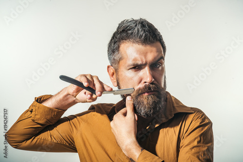 Fotografía Professional barber with thick beard and mustache, holding straight razor