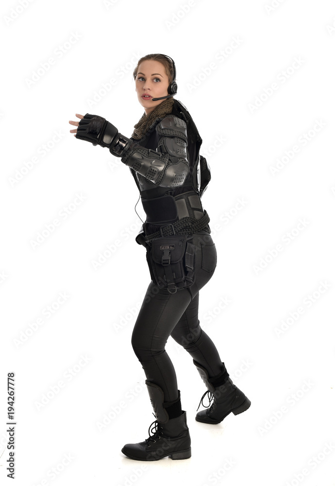 full length portrait of female  soldier wearing black  tactical armour with arms raised, isolated on white studio background.