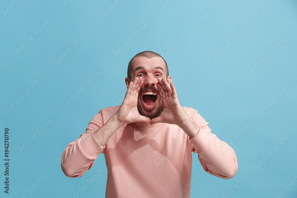 Isolated on pink young casual man shouting at studio