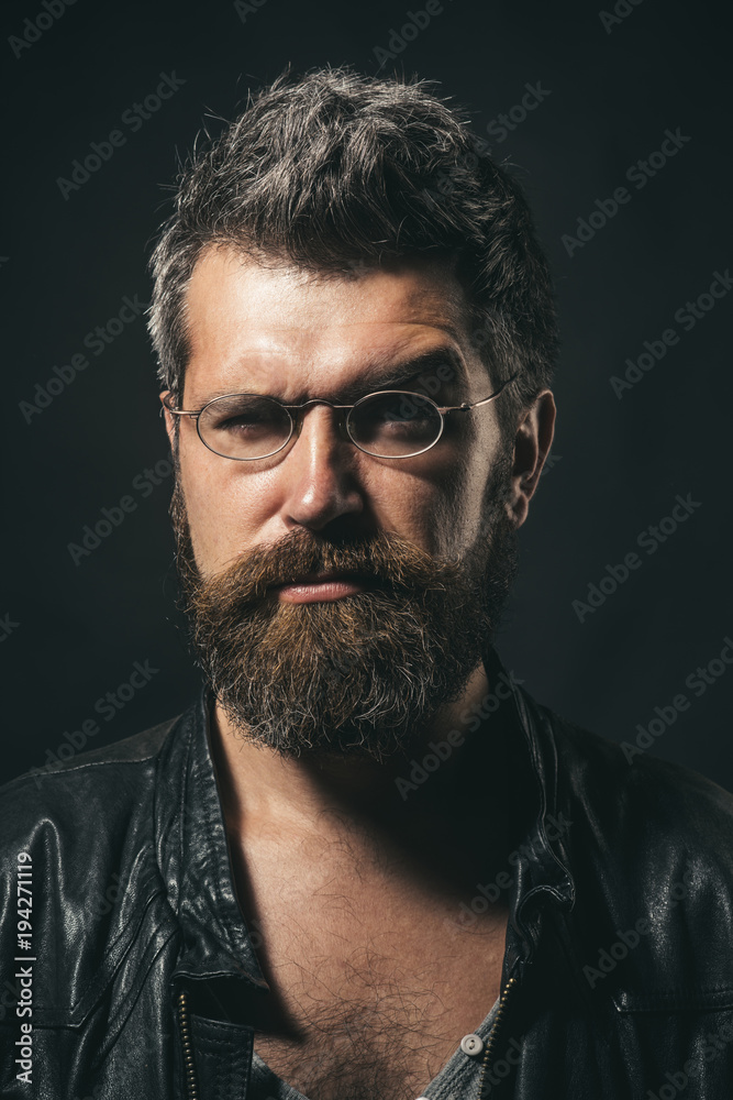 Fototapeta premium Stylish fashion man, confident attractive serious handsome hipster wears black leather jacket and stylish eyewear. Cool seductive man in leather jacket and fashionable glasses.People and style concept