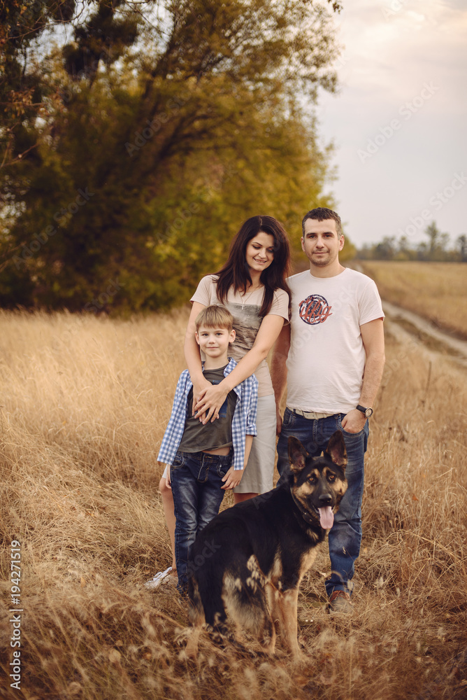 young family and their dog spend time on nature in the autumn afternoon