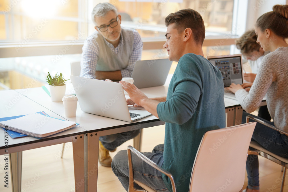 Teacher meeting around table with students