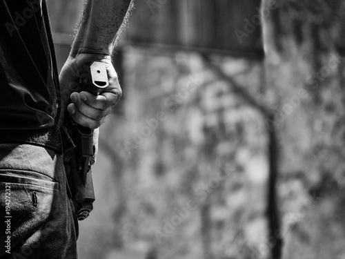 black and white image of male holding handgun in holster ready to shoot in shooting competion