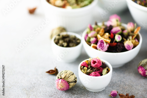 Assortment of dry tea in white bowls. Tea types backgound: green, black, floral, herbal, mint, melissa, ginger, apple, rose, lime tree, fruits, orange, hibiscus, raspberry, cornflower, cranberry