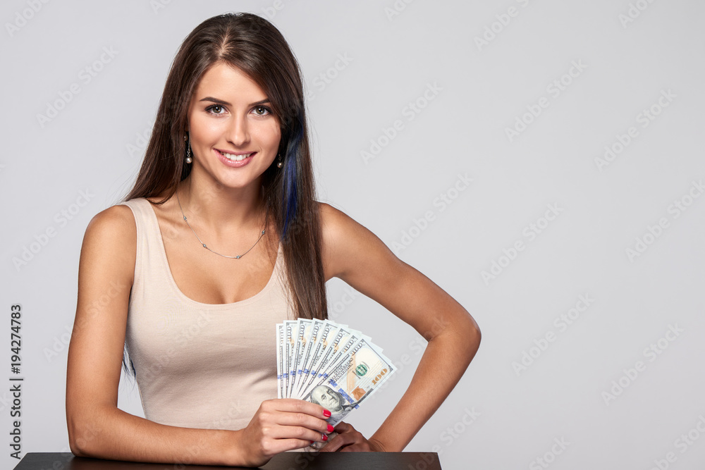 Woman with us dollar money in hand over grey background, with copy space Woman with us dollar money in hand over grey background, with copy space