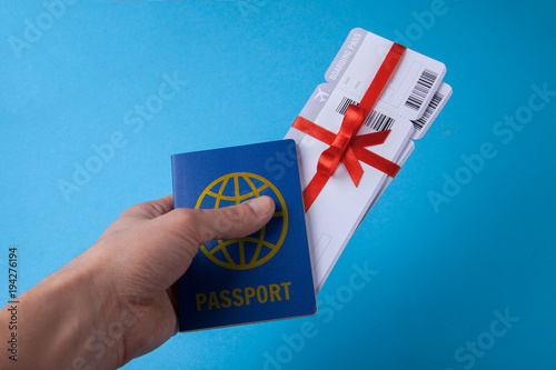 Man holds a passport in his hand and Air tickets as a gift with a red ribbon and bow. Passport with visas.