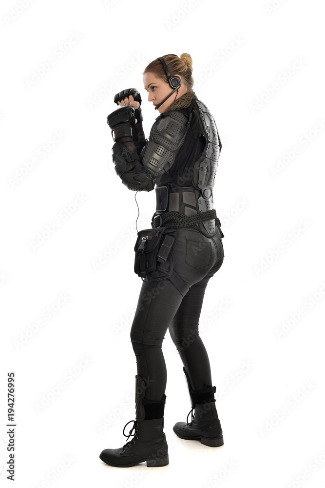full length portrait of female soldier wearing black tactical armour with arms raised, isolated on white studio background. full length portrait of female soldier wearing black tactical armour with arms raised, isolated on white studio background.