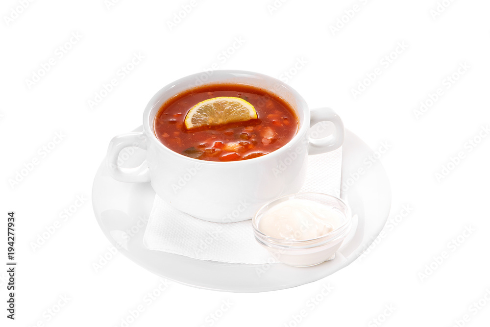 Solyanka, pickle with lemon and sour cream. On a napkin in a white plate isolated white. Serving dishes in a cafe, restaurant, for a menu. Side view Solyanka, pickle with lemon and sour cream. On a napkin in a white plate isolated white. Serving dishes in a cafe, restaurant, for a menu. Side view